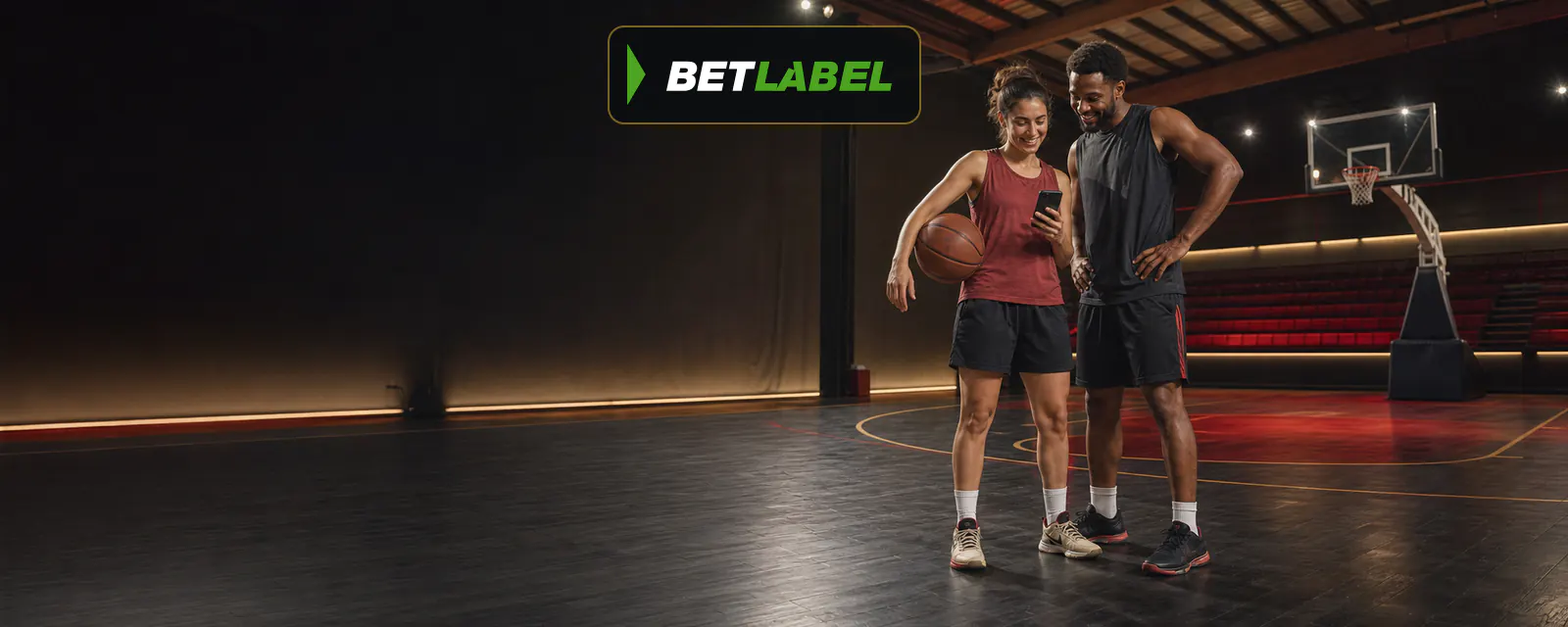 Baloncestista adulto consulta un teléfono móvil junto a la cancha